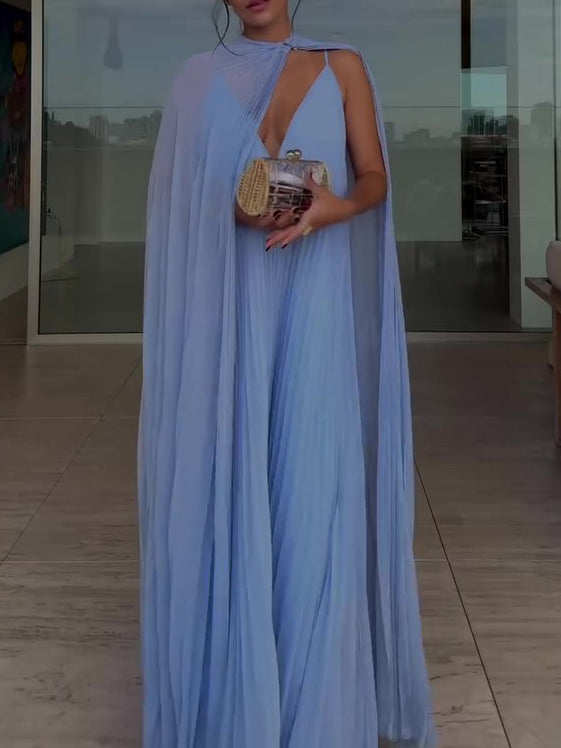 Woman in a blue evening gown with a cape holding a clutch in an indoor setting.