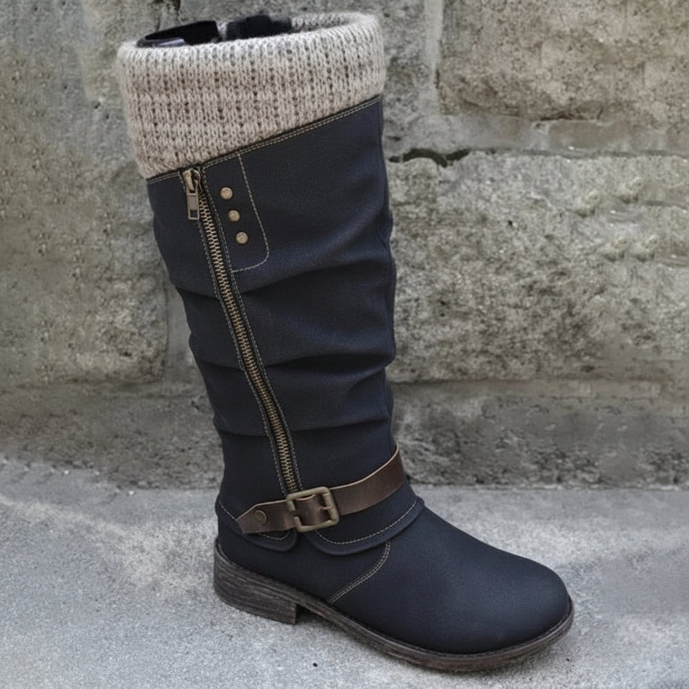 Black knee-high boot with a knit cuff on a stone surface