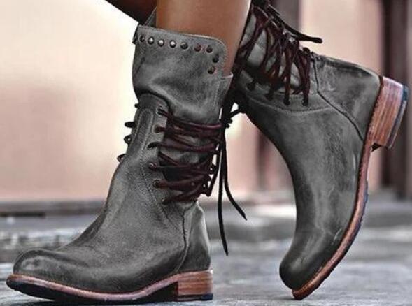 A pair of dark gray distressed leather lace-up ankle boots with brown laces and stacked wooden-look heels, shown worn on feet.