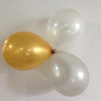 Two gold balloons and two white balloons tied together on a white background