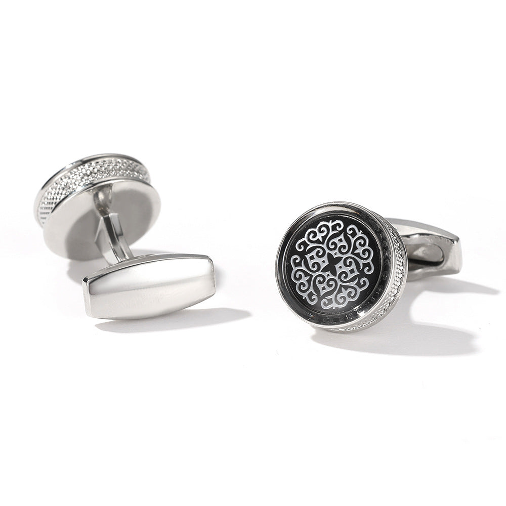 Silver cufflinks with intricate design on a white background