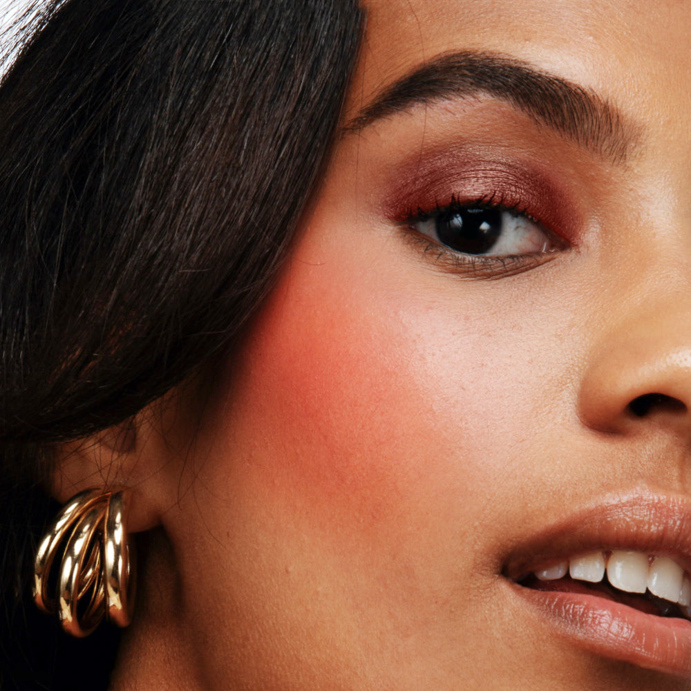 Close-up of a woman's face with gold earrings and makeup.