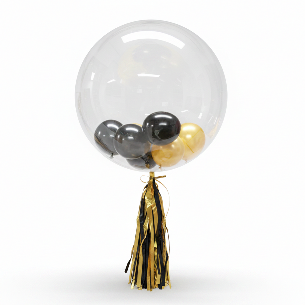 A clear round balloon with a black tassel, containing several metallic silver and yellow balloons inside, isolated on a white background.