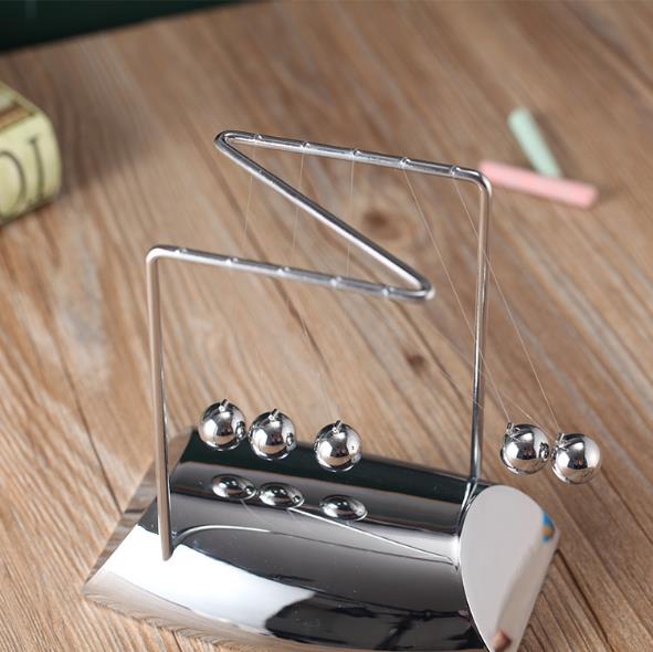 Metal earring holder with three silver earrings on a wooden surface