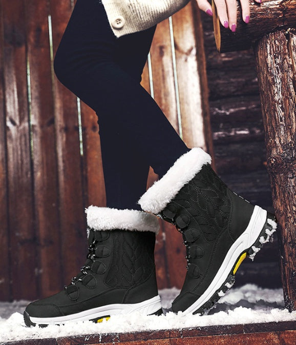 Person wearing black winter boots with white fur lining, standing on a snowy ground.