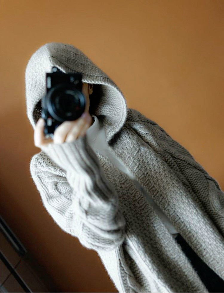Person wearing a gray hoodie holding a camera against a brown background