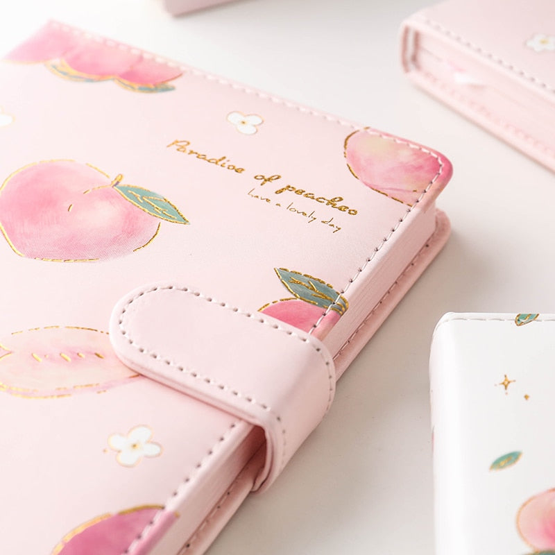 Pink notebook with peach illustrations on a light surface