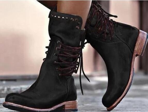 Black suede boots with brown soles worn by a person.