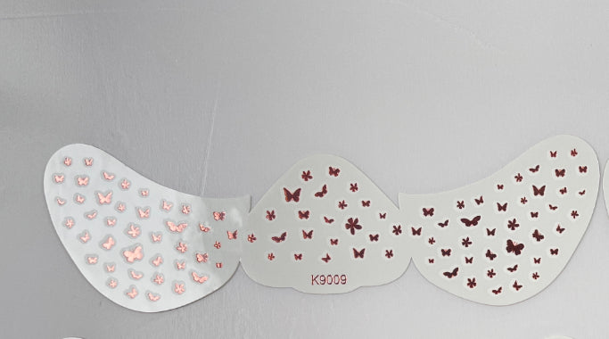 Butterfly wing-shaped nail art stencil with pink and red butterfly designs on a gray background