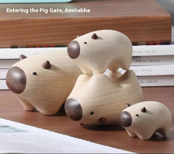 Three small wooden pig figurines in different sizes arranged on a wooden surface, with stacked books in the background and the text 'Entering the Pig Gate, Amitabha' at the top.