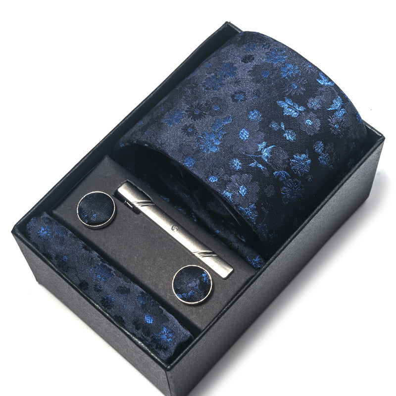 Tie, tie clip, and cufflinks set with blue floral pattern in a black box on a white background