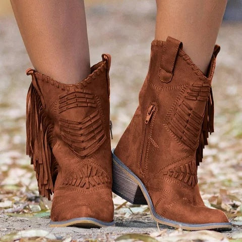 Brown fringe boots worn by a person on a blurred natural background