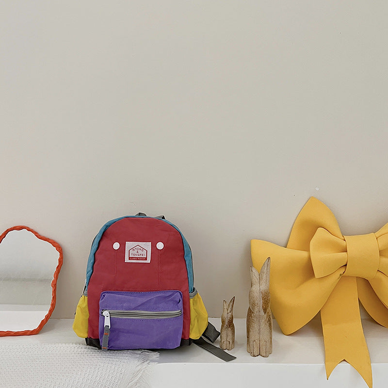 Colorful backpack with a purple compartment, red top, and yellow accents on a white surface.