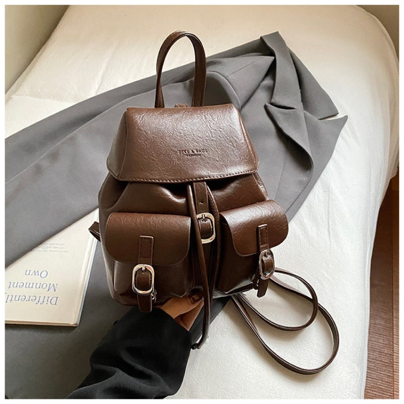 Brown leather backpack on a light surface with a gray garment