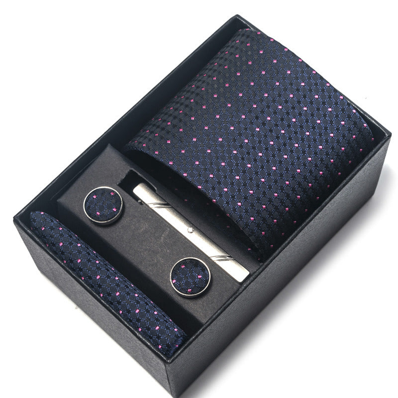 Navy blue tie with pink dots, cufflinks, and a tie clip in a black box on a white background
