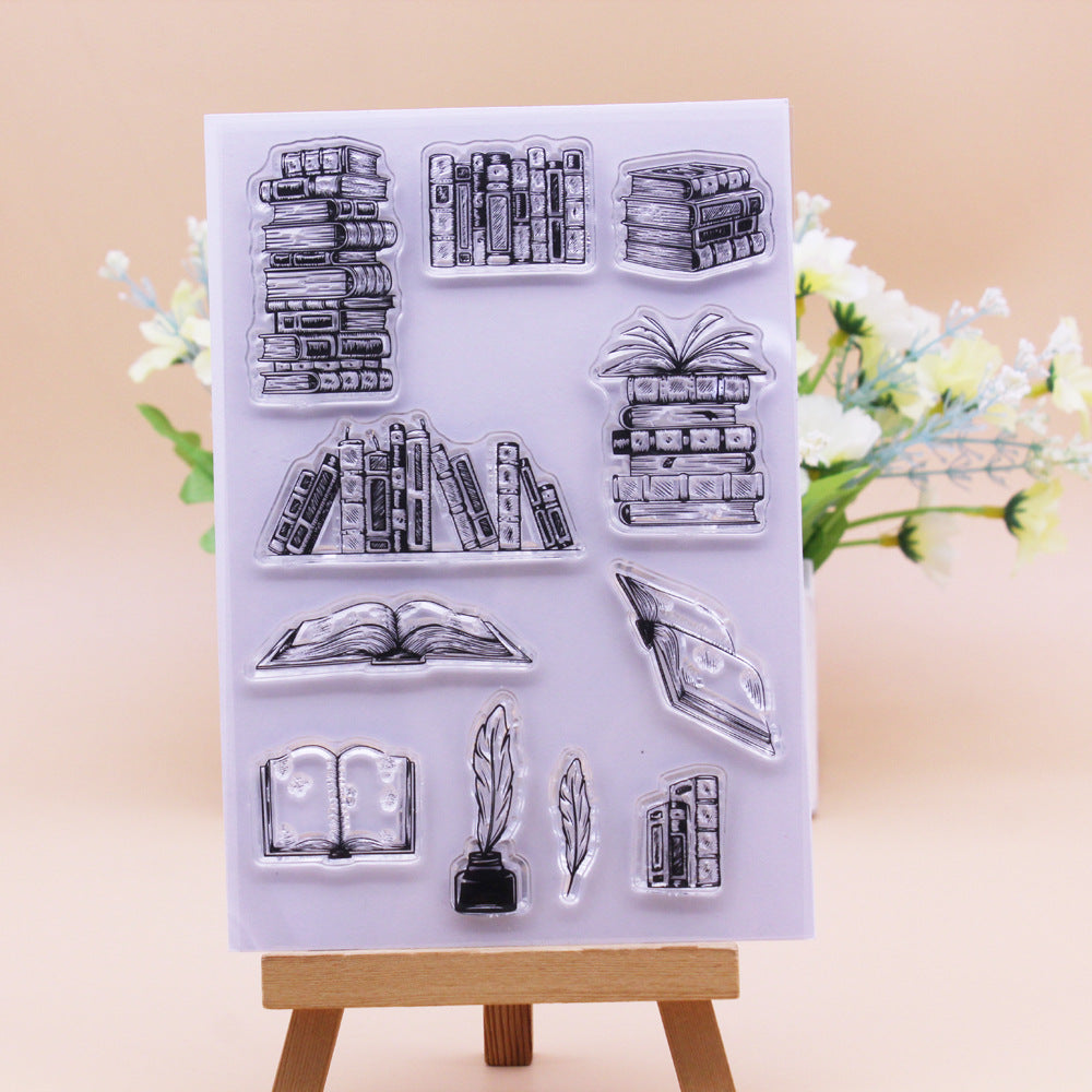 Clear stamp set with book and feather designs on a beige background