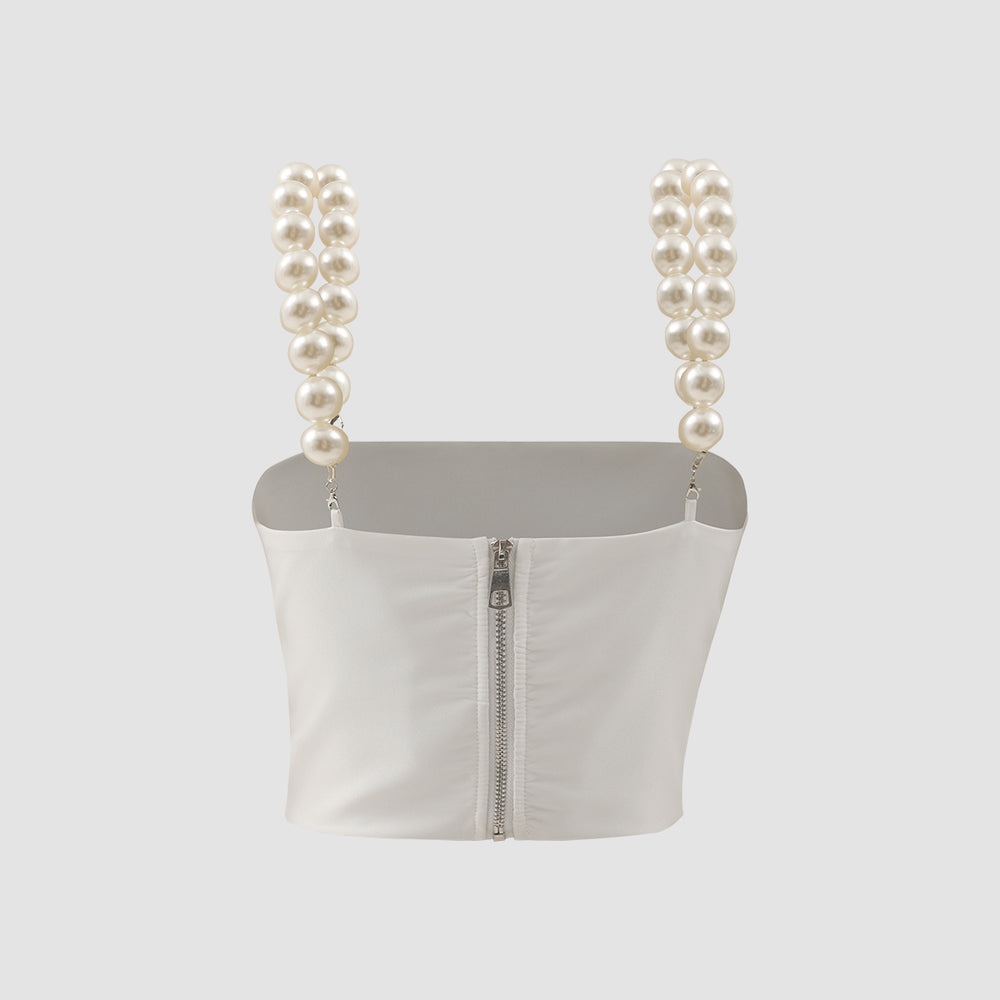 White top with pearl straps on a light gray background