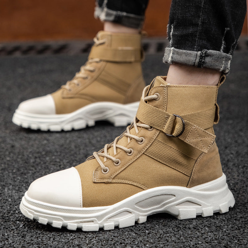 Tan tactical boots with white soles worn by a person on a dark surface