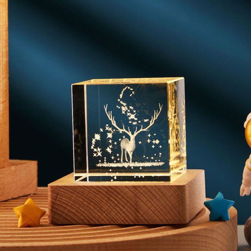 Decorative crystal block with engraved deer design on a wooden base against a dark background