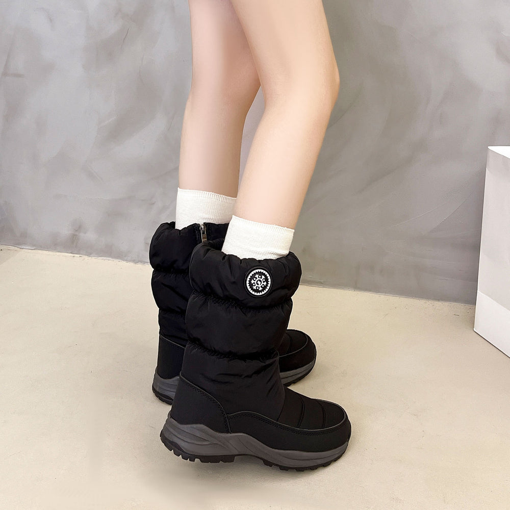 Black winter boots worn with white socks on a neutral background
