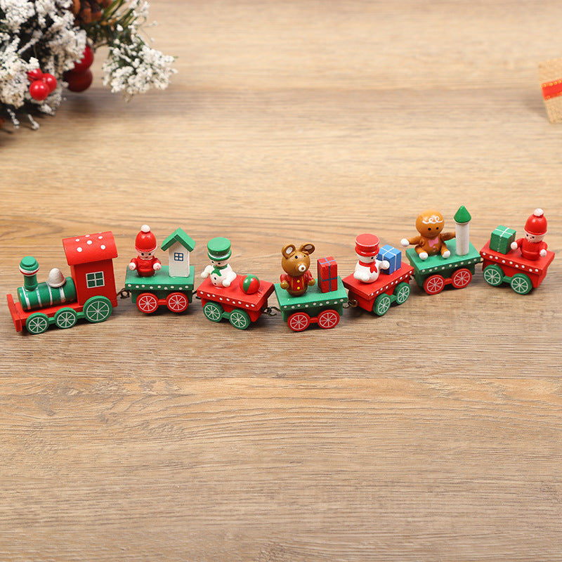 Wooden toy train set on a wooden surface with Christmas-themed decorations.