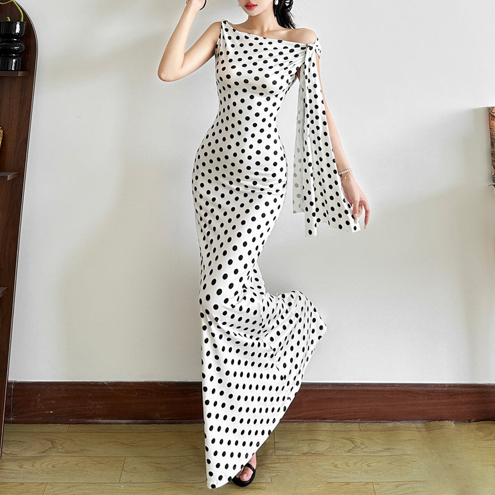 Woman wearing a polka dot dress against a plain wall.