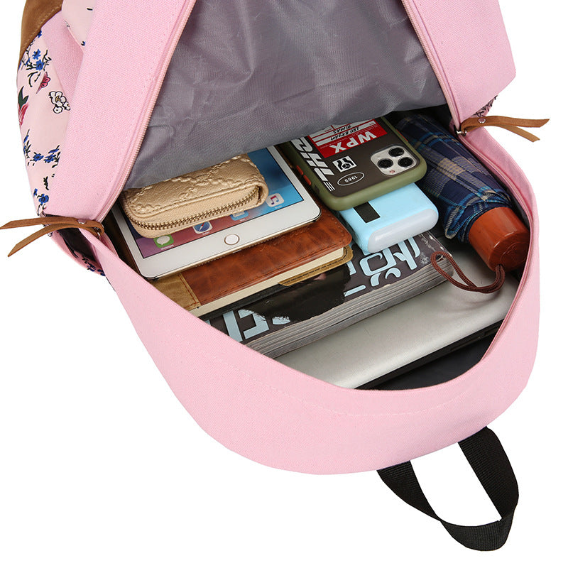 Pink backpack with various items including a tablet, phone, and books.