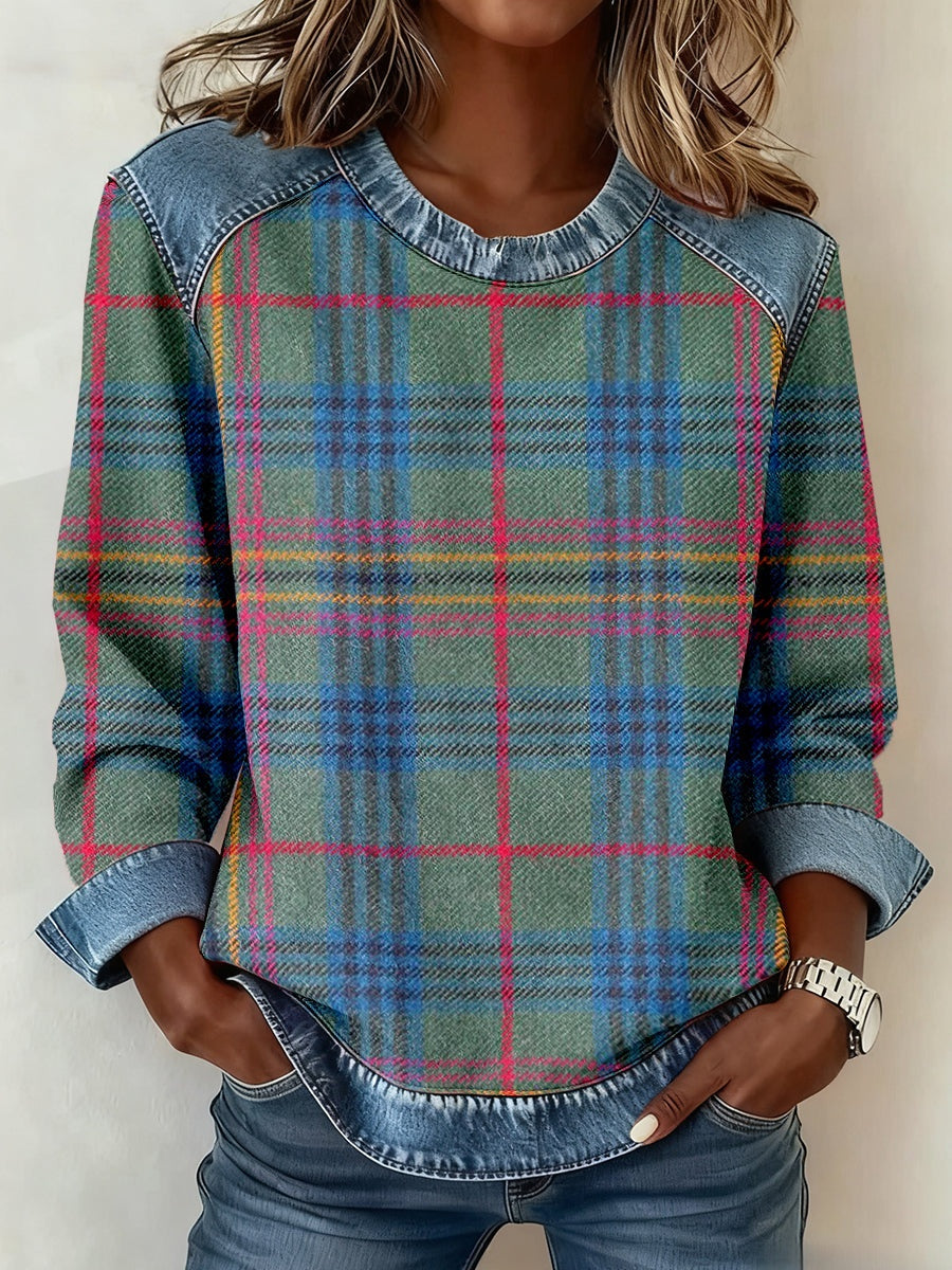 Person wearing a plaid shirt with denim sleeves against a neutral background