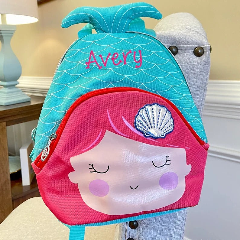 Mermaid-themed backpack with 'Avery' embroidered on it, held by a person.