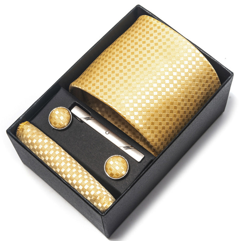Gold tie, cufflinks, and pocket square set in a black box on a white background