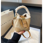 Beige handbag with fur handle held by a person, with a 'THANK YOU' bag in the background.