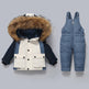Children's winter jacket with fur hood and blue snow pants on a gray background