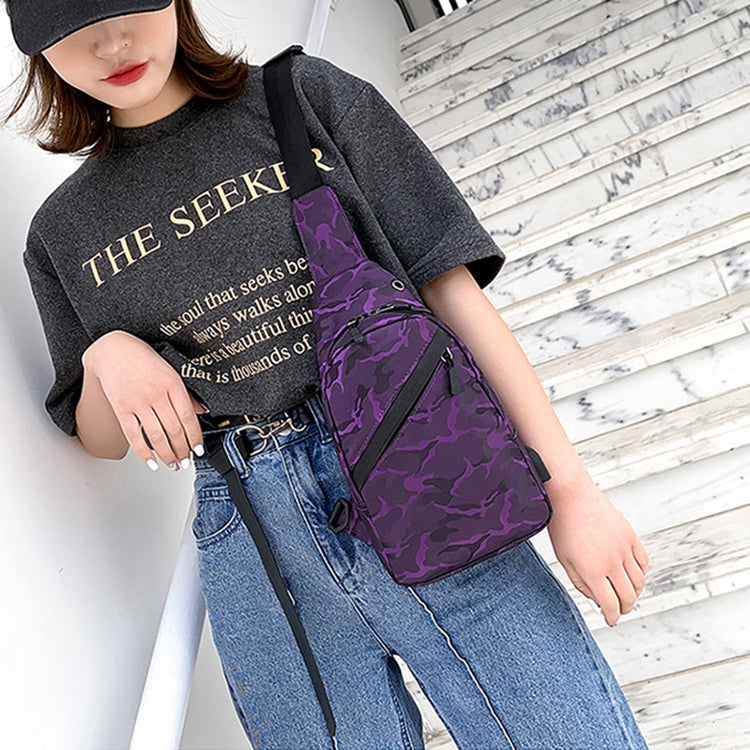 Person wearing a black shirt with text and blue jeans, carrying a purple camouflage-patterned bag.
