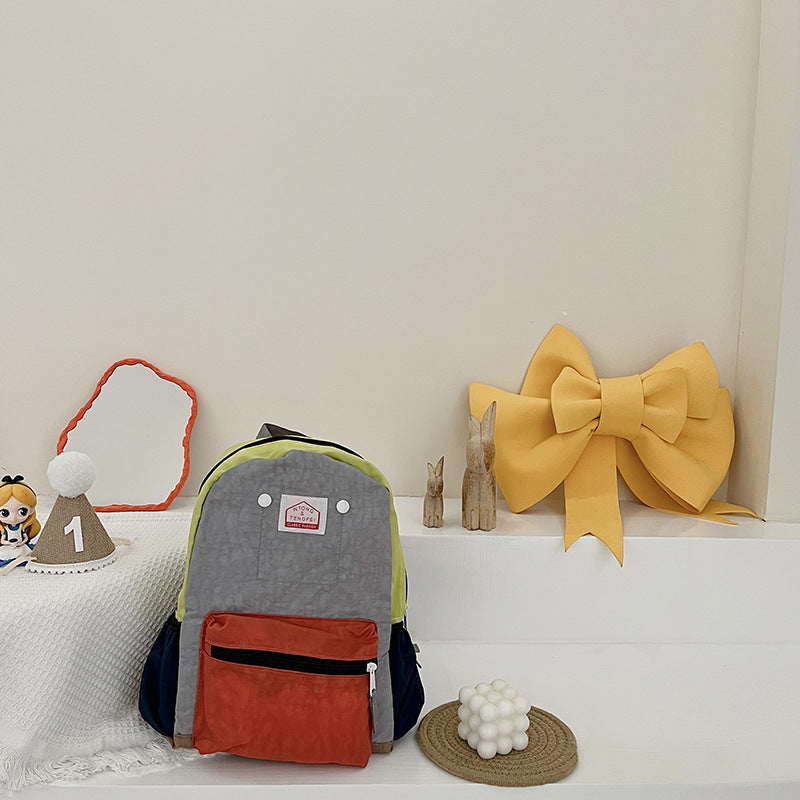 Gray and red backpack with a yellow bow on a white surface
