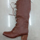 Brown knee-high boot with laces on a light gray background