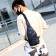 Person wearing a navy sling bag in an urban setting