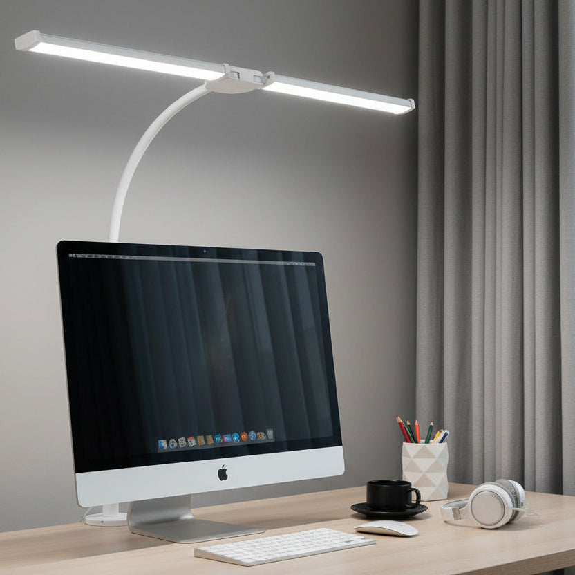 Desk lamp on a desk with a computer monitor and laptop in the background