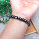 Black beaded bracelet on a wrist with a natural background