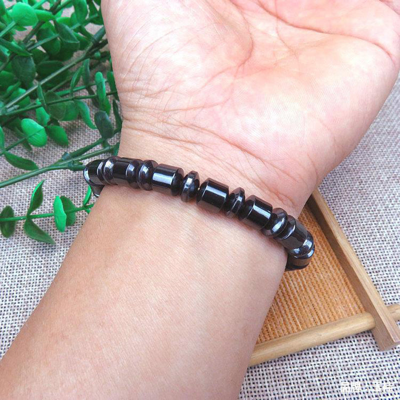 Black beaded bracelet on a wrist with a natural background