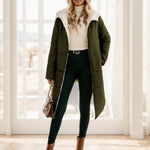Woman wearing a green puffer coat, white turtleneck, black pants, and brown boots in a bright room.