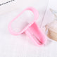 A pink plastic bottle opener resting on a textured white fabric surface with a partial magazine or card visible in the background.