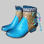 Pair of colorful boots with blue soles on a cardboard surface in an indoor setting.