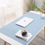 Desk with a blue mat, laptop, and decorative items in a home office setting.