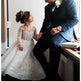 Man in a suit and a young girl in a white dress sitting together.