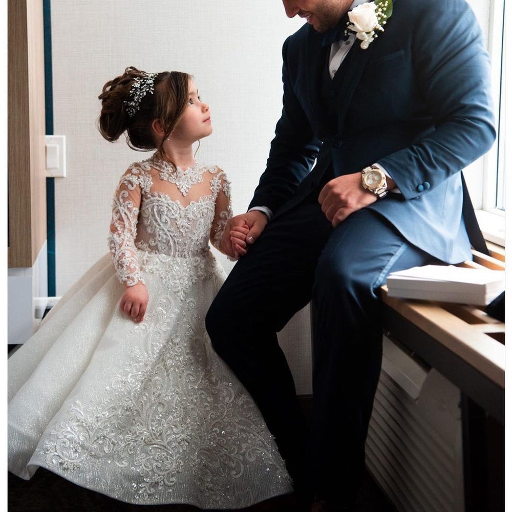 Man in a suit and a young girl in a white dress sitting together.