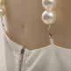 White garment with pearl-like beads on a beige background