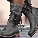A pair of dark gray distressed leather lace-up ankle boots with brown laces and stacked wooden-look heels, shown worn on feet.