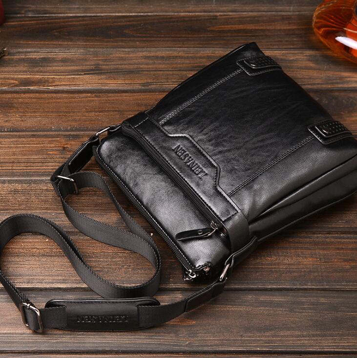 Black leather bag with a strap on a wooden surface