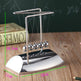 Metal Newton's cradle on a wooden surface with measurements displayed
