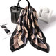 Patterned scarf with black handbag, sunglasses, and white box on a white background